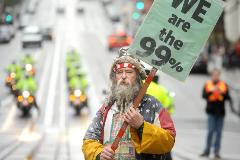 An Occupy protester picketing outside a Bank of America branch on Friday, January 20, 2012, in San Francisco. The US is among the most unequal societies among developed nations, yet it ranks 15th happiest according to the happiness index [Noah Berger/AP Photo]