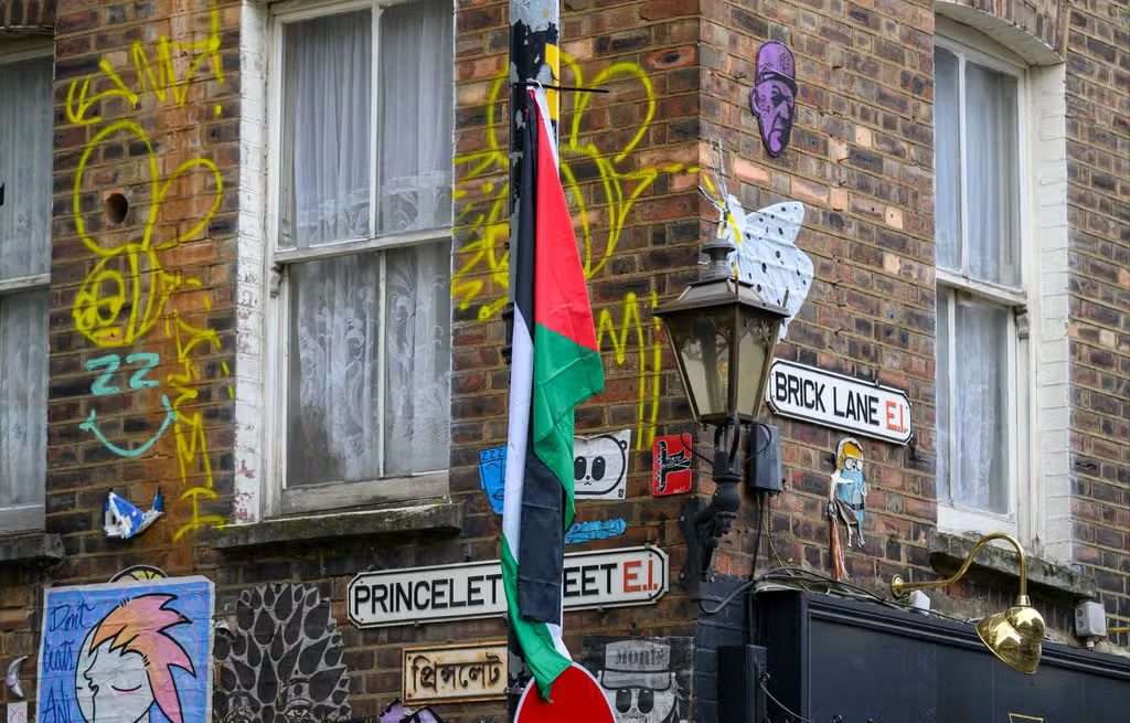 https://dazzlingdawn.com/wp-content/uploads/2024/03/A-PALESTINIAN-FLAG-ATTACHED-TO-A-LAMPPOST-IN-BRICK-LANE.jpg