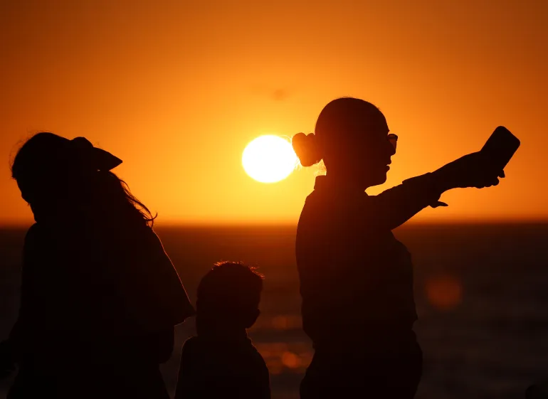 https://dazzlingdawn.com/wp-content/uploads/2024/04/People-are-silhouetted-at-sunset-as-they-visit-the-Malecon-one-day-before-a-total-solar-eclipse-in-Mazatlan-Mexico.webp